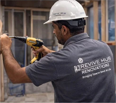 Revive Hub renovation worker applying professional waterproofing tanking membrane to a Dubai villa basement wall — structural moisture protection system for post-flood damage prevention